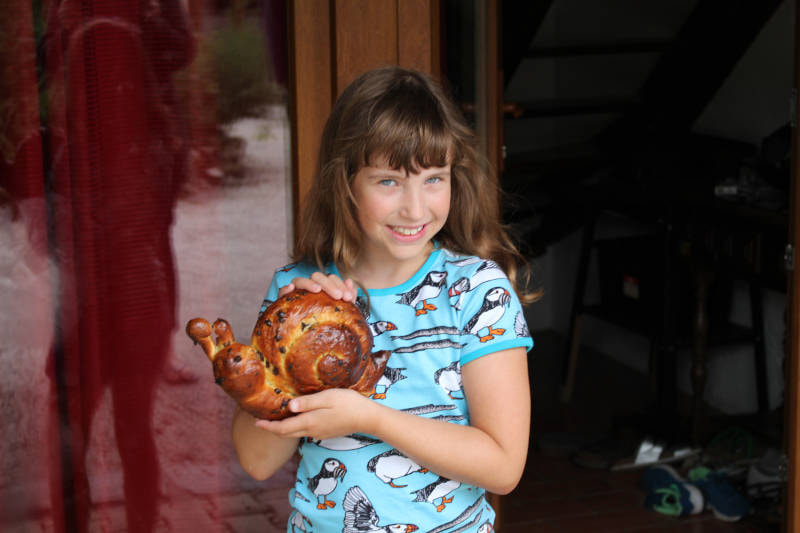 girl holding a bread in a shape of a snail